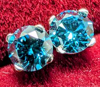 Close view of both blue diamond studs in 14K gold prong settings