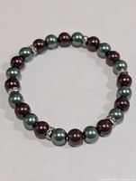 Full view of bracelet showing alternating teal and purple dyed pearls with rhinestone spacers