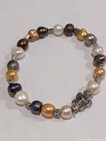 Full view of bracelet laid flat showing pearls, spacers and butterfly charm