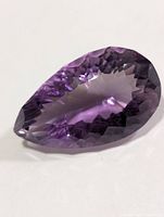 Loose faceted pear-shape purple gemstone on white background