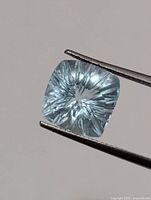 Close-up of aquamarine held by tweezers showing starburst cut