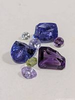 Group of seven loose faceted gemstones on neutral background