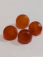 Four round reddish-orange Carnelian stones on white background