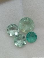 Four round emeralds positioned together on white background