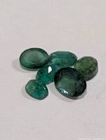 Six loose emeralds close-up view showing cuts and color