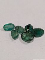 six oval emerald gemstones on white surface