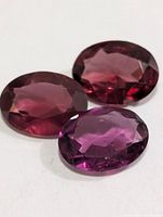 Close-up of three oval faceted garnets showing color and cut