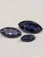 Three marquise-cut iolite gemstones on neutral background