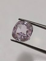 Close-up of cushion cut kunzite held by tweezers
