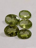Five loose peridot gemstones laid out