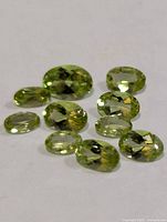 Group of loose faceted peridot stones on white surface