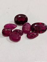 Group of eight loose faceted ruby gemstones on white background