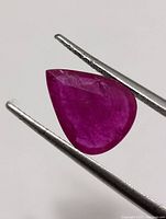 Close-up of pear-shaped ruby held by tweezers