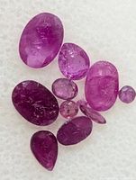 Ten loose faceted rubies on white background, various shapes