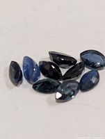 Eight loose marquise blue sapphires on white surface