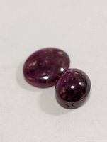 Close-up of both star ruby cabochons showing color and surface
