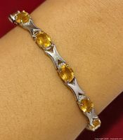 Bracelet on wrist showing citrine stones and X-shaped silver links