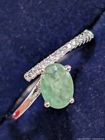 Front view showing oval green center stone and clear accent stones on band