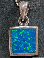front view of square silver pendant with blue-green opalite cabochon