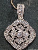 front view of silver pendant showing openwork design and CZ stones