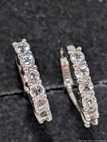 Front view of both hoop earrings showing white topaz settings