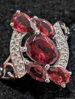 Front view of silver ring with oval and pear garnets and clear accents