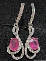 Front view of silver drop earrings with ruby centers and CZ accents