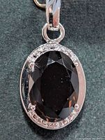 Front view of oval smokey quartz silver pendant with accent stones