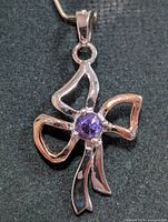Front view of silver bow pendant, amethyst center visible