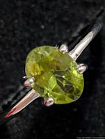 Angled close-up of ring showing peridot stone and prongs