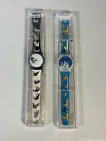 Both Swatch watches in original cases, front view