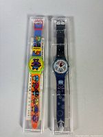 Two Swatch watches in cases, front view