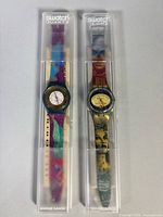 Two Swatch watches in clear cases
