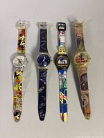 Four wristwatches laid out side by side showing straps and dials