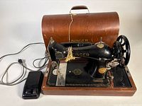 Full view of Singer sewing machine on wood base with pedal and carrying cover