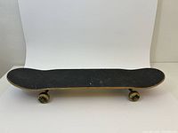 Side profile of skateboard showing grip tape top and wheels