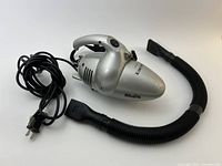 Handheld vacuum with hose and nozzle displayed