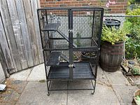Front view of assembled two-section small-animal cage showing overall structure, levels, doors, and wheels