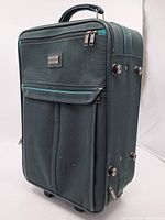 Front view of dark teal American Tourister soft-side upright suitcase showing overall design and front pocket