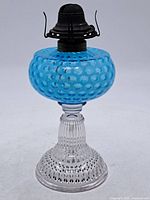 Full view of lamp showing blue font, clear base, and metal burner