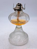 Full view of glass oil lamp showing overall form and residual fluid