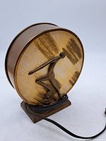 Front view of circular disc lamp showing dancer relief, cord visible