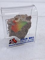 Front view showing painted concrete fragment in acrylic display with printed label