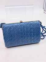Front view of blue woven clutch showing exterior and strap