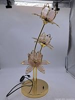 Front view showing three glass-petal flower heads on brass gold-plated stems and base