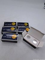 Six boxes of cardboard coin holders, one opened to show internal holders