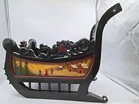 Right side view of carved wooden sleigh showing painted rural scene and scroll crest