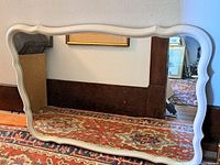 Front view of mirror showing scalloped white frame and glass