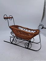 Side view of wicker sleigh showing basket body and metal runners