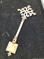 Full view of brass Coptic cross showing lattice head, handle, and square base